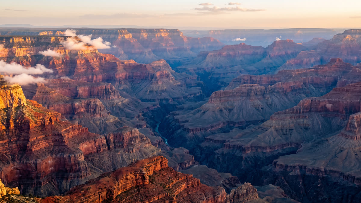Panoramic Grand Canyon view at golden hour with layered red sandstone cliffs and morning haze