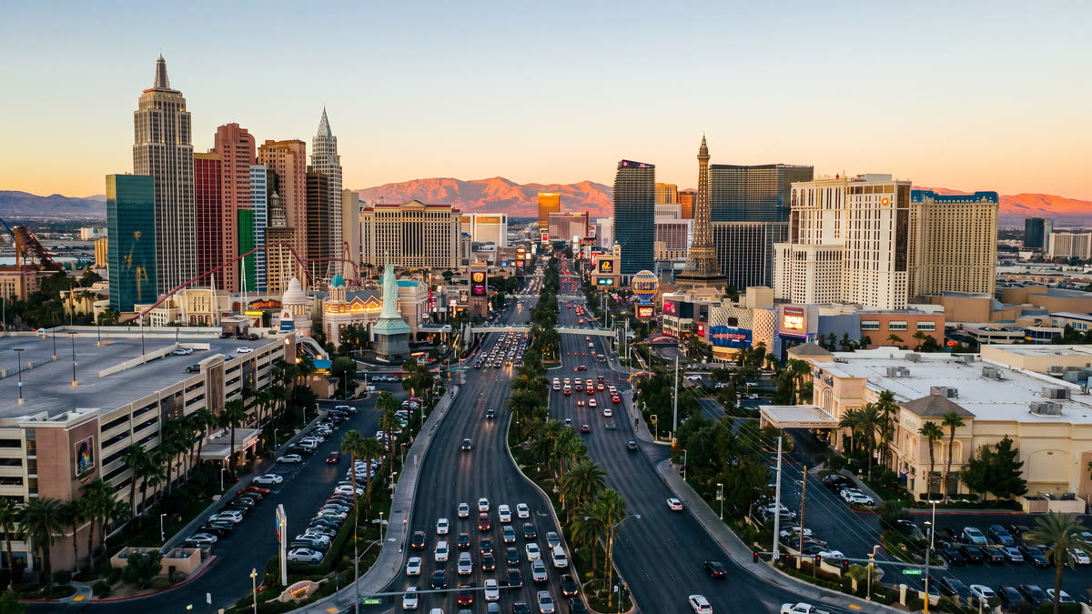 Cinematic aerial view down the full length of the Las Vegas Strip at dusk with resort towers curving south